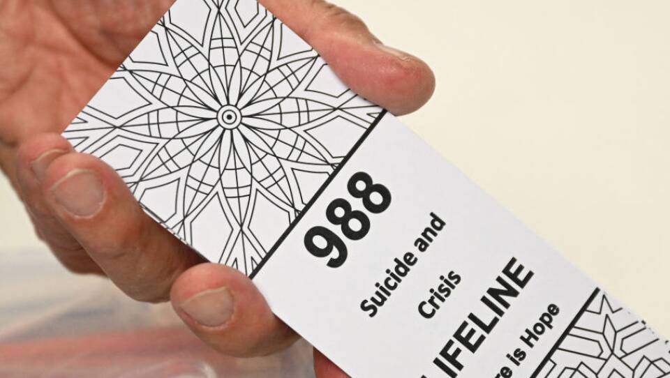 A bookmark advertising the 988 suicide and crisis lifeline emergency telephone number displayed by a volunteer with the Natrona County Suicide Prevention Task Force, in Casper, Wyoming on August 14, 2022.