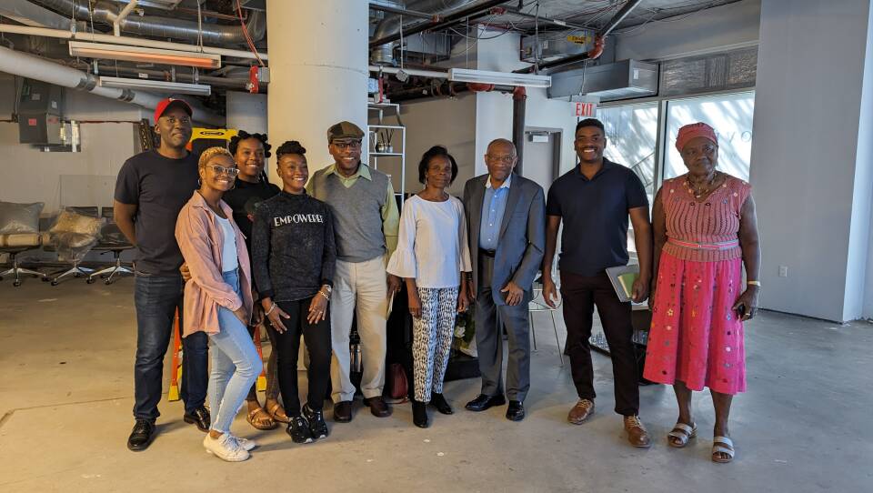 About 10 people smile for the camera in an empty space