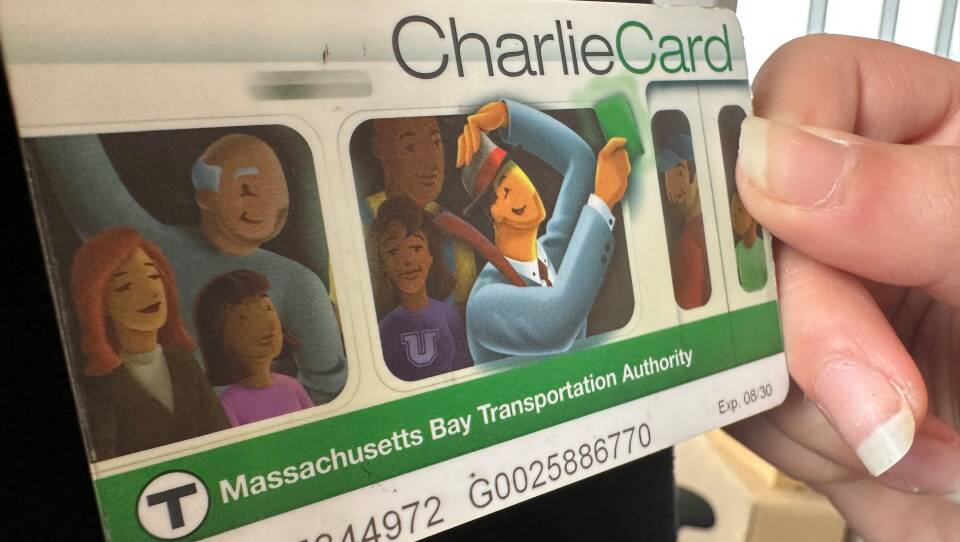 A person holds a plastic CharlieCard up to a reader.