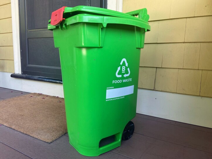 A bright green bin labeled "food waste" with wheels and a latching lid.