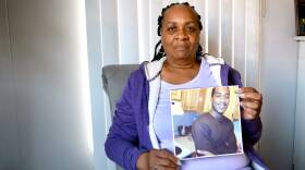 Robin McGregor sits facing the camera, holding a picture of her son Clarence, who was shot and killed in 2014 in Dorchester.