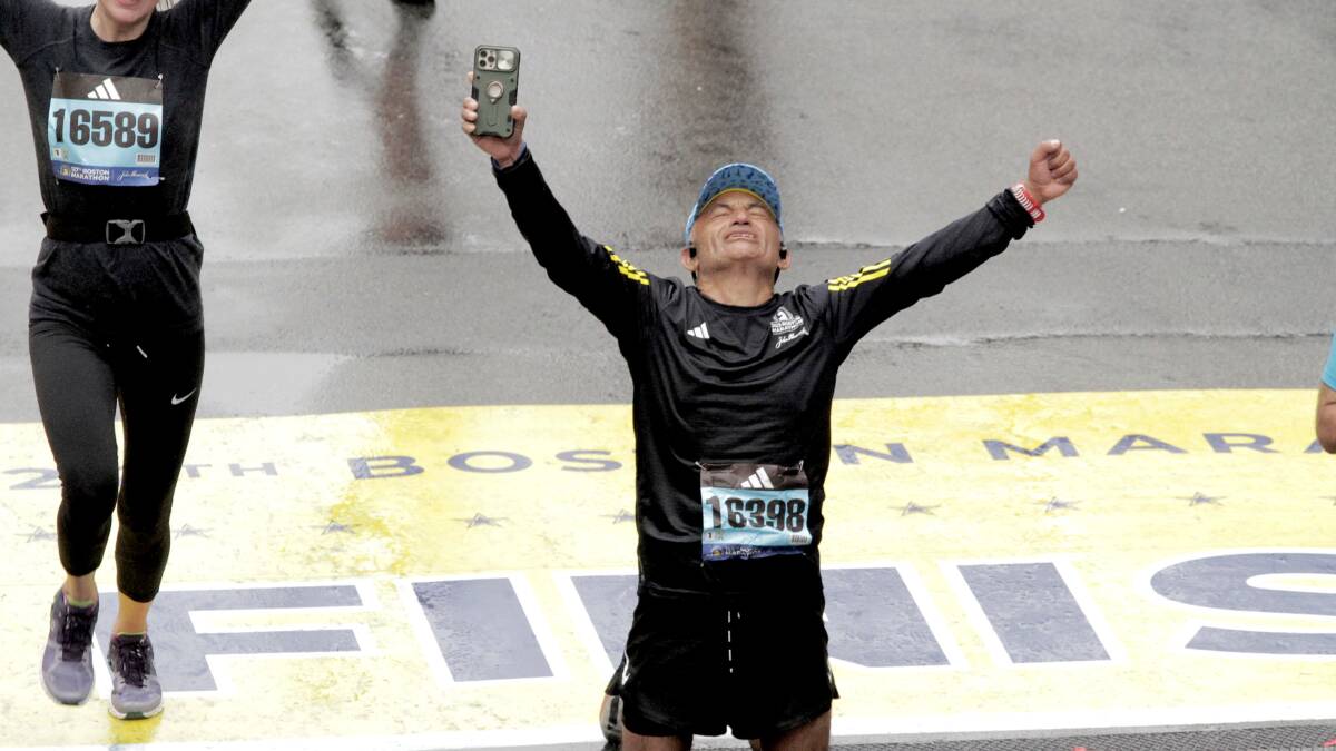 A man with his arms thrown up in the air has a face of triumph, exhaustion and relief.