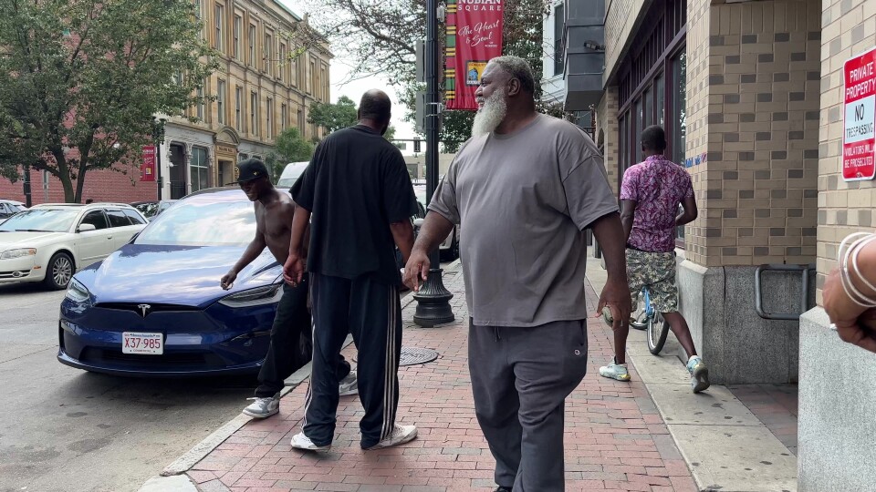 Large African American man in T-shirt walking down the street smiling
