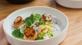 White bowl filled with sliced snap peas, julienned apples, sliced apples, and seared scallops topped with black sesame seeds