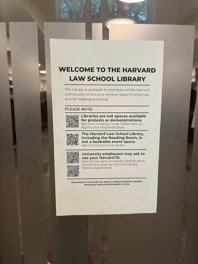 A sheet of paper says "Welcome to the Harvard Law School Library" before noting "libraries are not spaces available for protests or demonstrations."