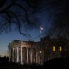 The sun starts to rise behind the White House, giving it a faint glow.
