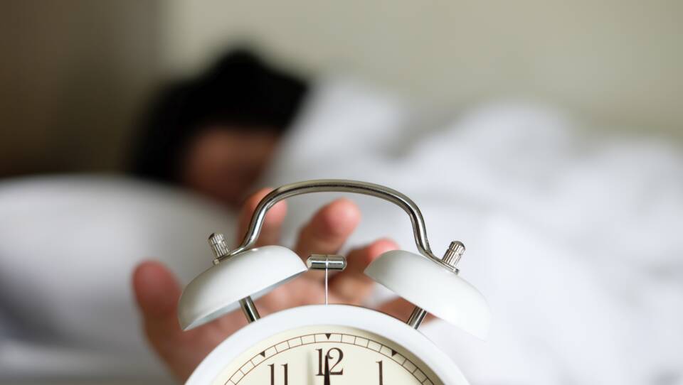 Person Turning Off Alarm Clock
