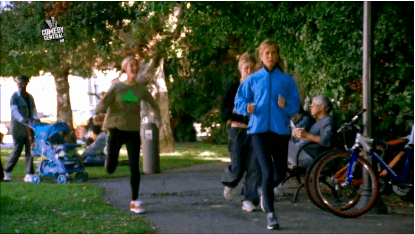 A woman runs goofily through a park