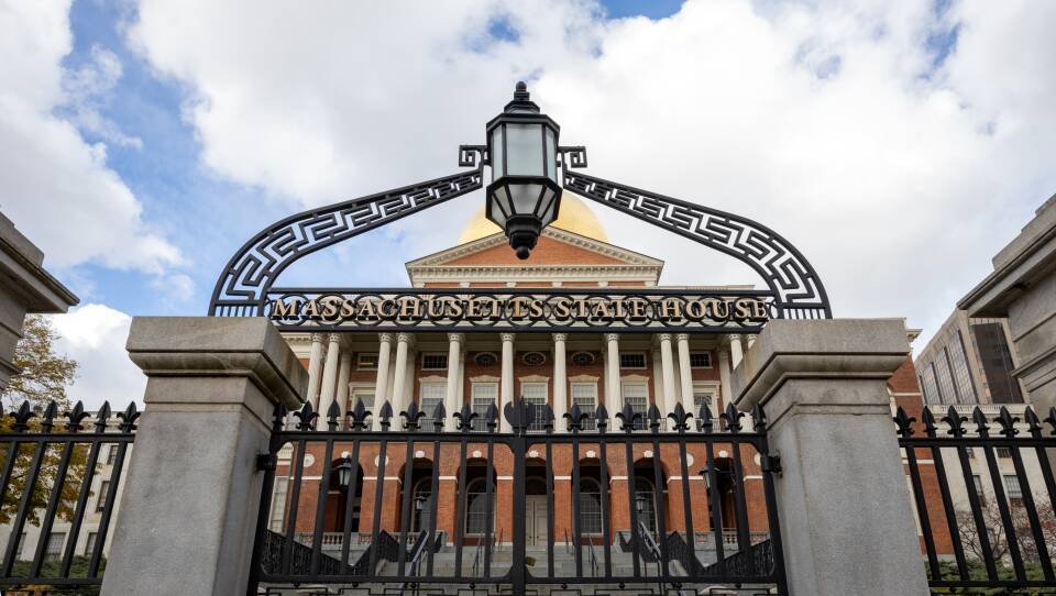 A black iron gate blocks with a lantern over the arch blocks the stairs into the Massachusetts State House.