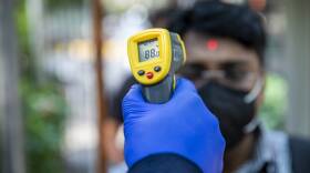 An office worker is screened with an infrared thermometer as he enters a building in New Delhi, India.
