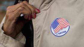 A woman pulls her fall jacket taut to show her voting sticker