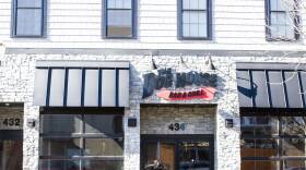 The outside of a Woburn restaurant called The Dog House Bar and Grill with an American Flag hanging to left of it.