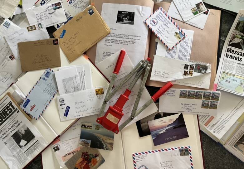 A red-and-silver metal tool on top of a pile of letters and postcards.