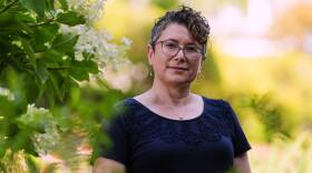 A woman poses amid leafy greens.
