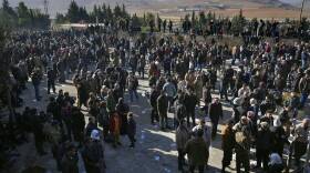A group of people stand in a dirt field.