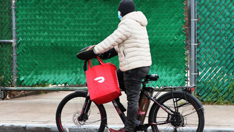 A DoorDash delivery person rides their bike in New York City. Workers across the country went on strike on July 31 to demand higher pay and tip transparency.