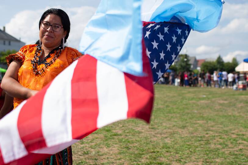 A woman smiles for the camera while waving flags