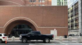 A pickup truck is parked outside a large brick building with an archway door.