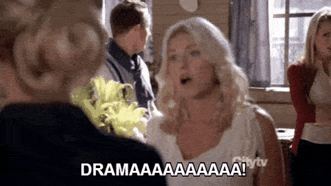 A man in the background of a crowd spins around and exclaims "Dramaaaaaaaa!" with a flourish