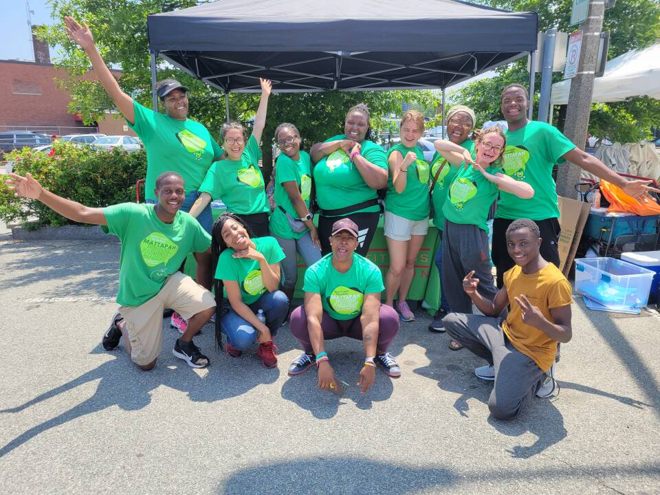 About a dozen people in matching green T-shirts smile and pose for the camera.