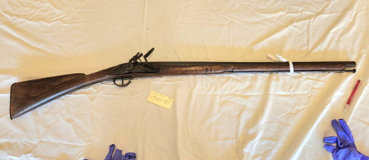 An old flintlock musket sits on a table.
