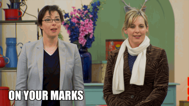 The hosts of the Great British Baking Show say "On your marks, get set, bake!"