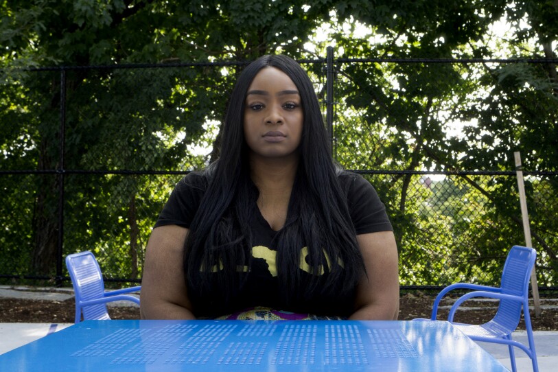 A woman with long black hair sits at a blue table.