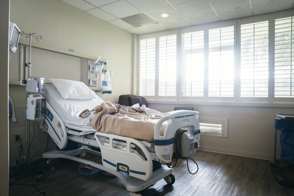 Empty hospital bed near sunny window