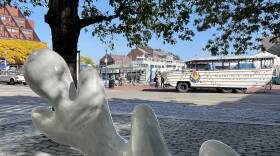 One of five large marble leaves on display at Boston's Central Wharf Park sits in front of a duck boat.