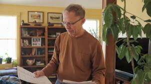 Chappaquiddick resident Bob Fynbo reads the insurance policy that has become his "major" expense. "We're at the point where we have to do without stuff," he said.