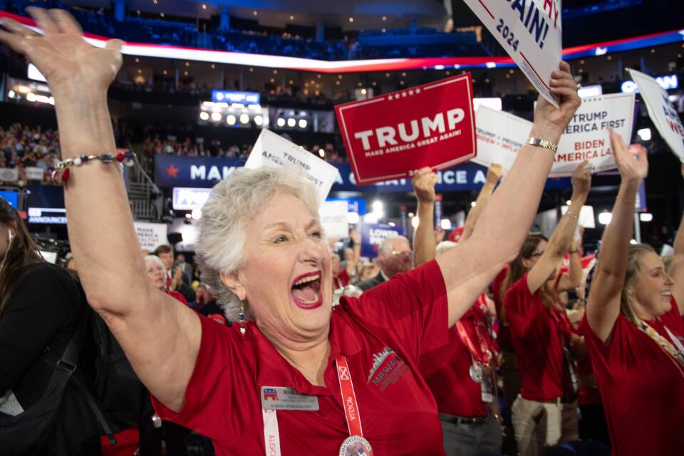 A woman in a red polo shirt yells in excitement on the convention floor.