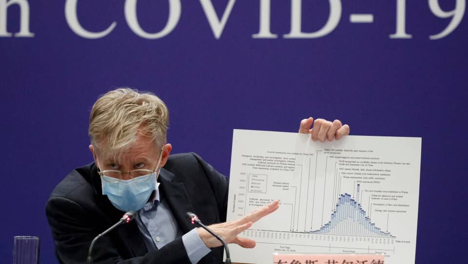 Bruce Aylward of the World Health Organisation holds a chart about the COVID-19 outbreak during a briefing in Beijing, China, Monday. The WHO says the virus has not risen to the level of a pandemic.