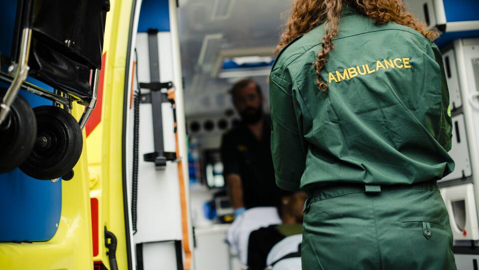 Paramedics moving a patient on a stretcher into an ambulance