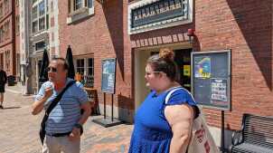 Russ and Joan stand outside a theater on a brick sidewalk