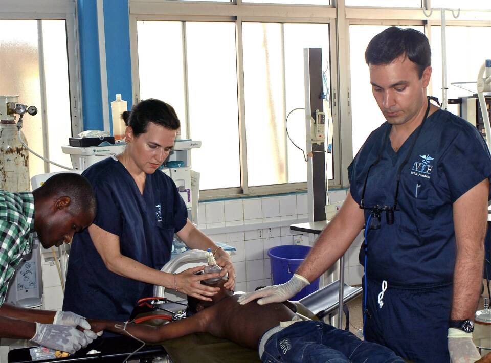 Three people stand around a child with a breathing apparatus on their face.
