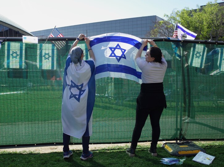 Two counter-protesters hang an Israeli flag on the fencing surrounding MIT's pro-Palestine encampment in Cambridge, May 7, 2024