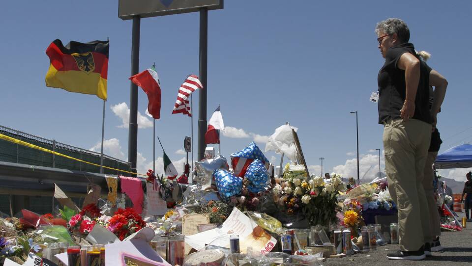 Mourners visit a makeshift memorial on Aug. 12, 2019, near the Walmart in El Paso, Texas. On Monday a Texas prosecutor, facing mounting criticism over the handling of the shooting, resigned after the county took the extraordinary step of moving to remove her from elected office.