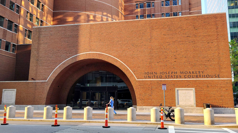 A large brick courthouse with a pedestrian walking by.