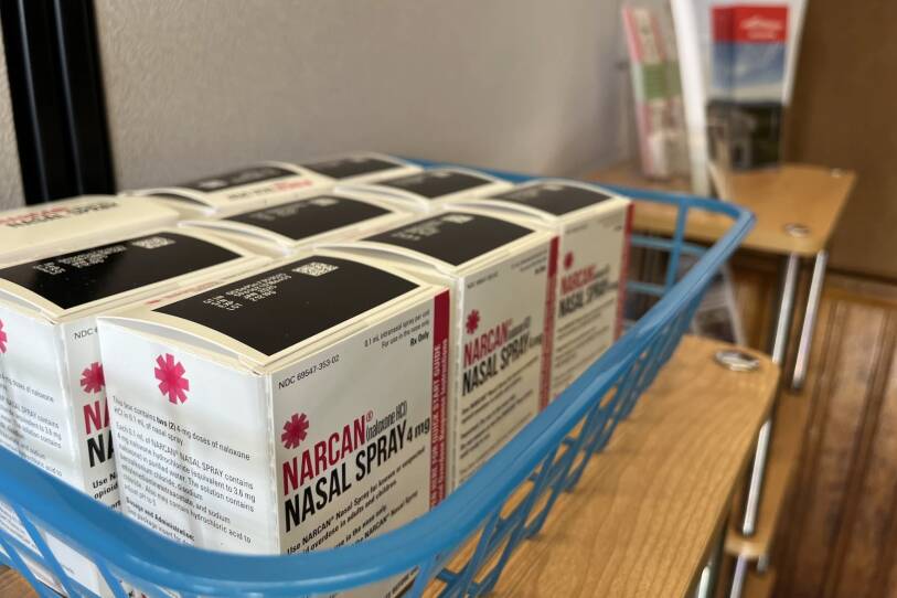 Several small boxes labeled "NARCAN nasal spray" are lined up in a plastic bin.