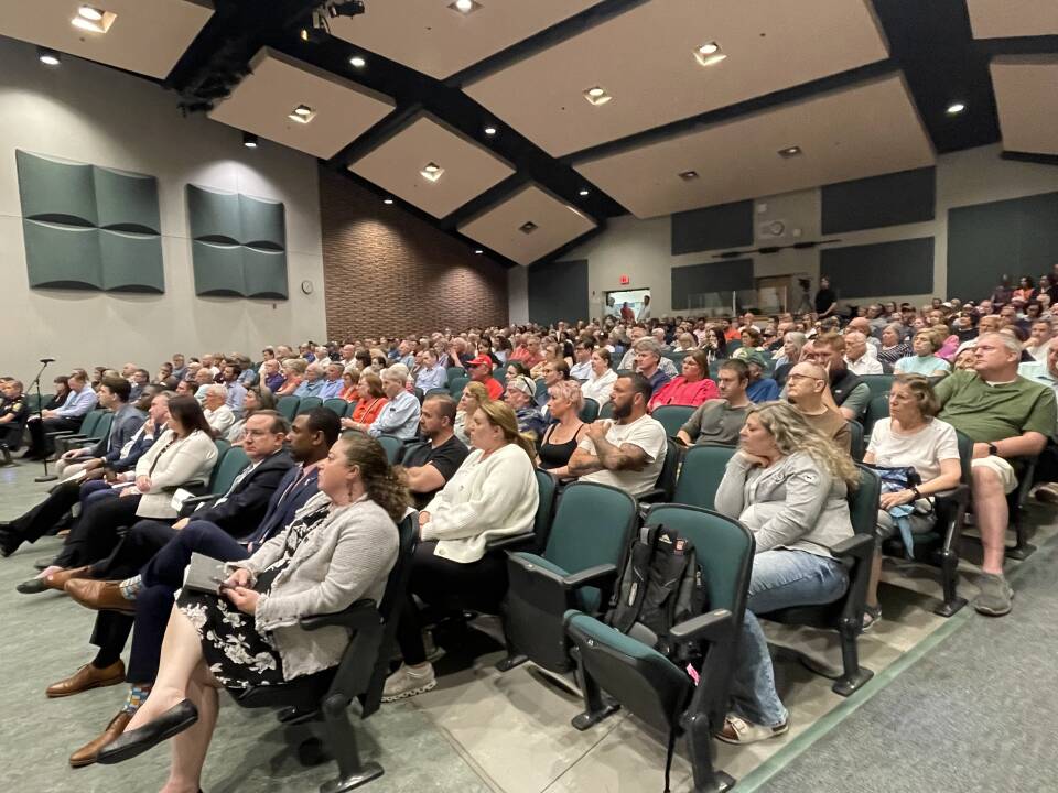Hundreds of people in auditorium-style seating fill a large meeting room.