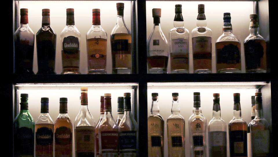 Two backlit shelves stocked with liquor bottles.