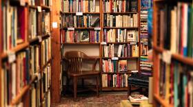 A warmly lit small bookstore with a wooden chair.