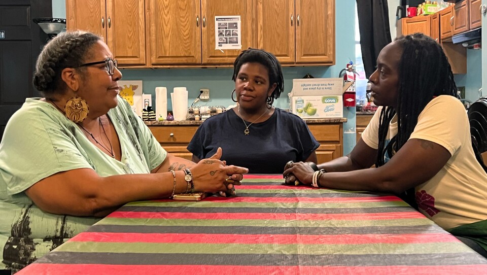 Three women sit a table talking.