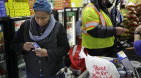 A woman places a card back in her wallet at the checkout line of a grocery store.