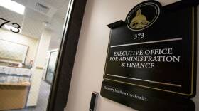 A sign on an office door has a picture of the State House gold dome over the words "Executive Office for Administration & Finance"