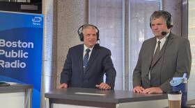 Two men in suits stand at a desk