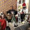 A woman poses inside her office surrounded by dozens of Black Santa toys and figurines.