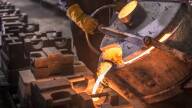 Worker pouring molten steel into moulds in foundry