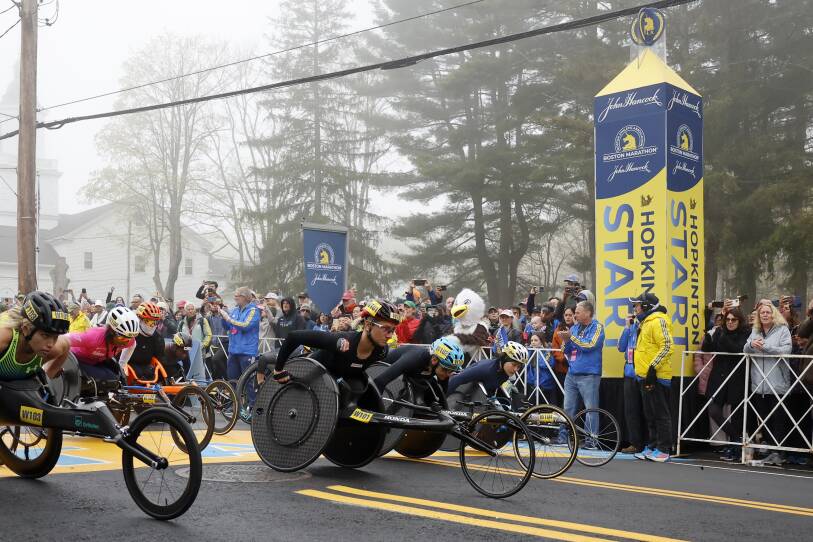 A group of wheelchair athletes at the finish line. They are surrounded by heavy fog.