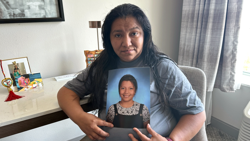 In a hotel room, a woman holds a photo of her daughter who died.